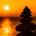 Balanced pebble pyramid silhouette on the beach on sunset.