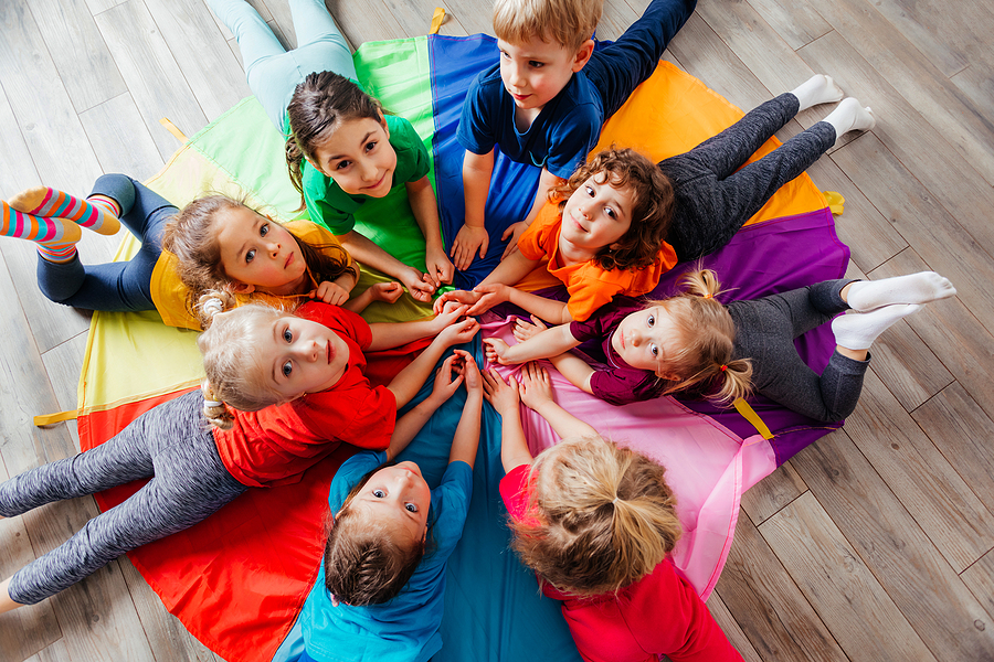 Preschool Children at little explorers class laying on a colorful parachute.