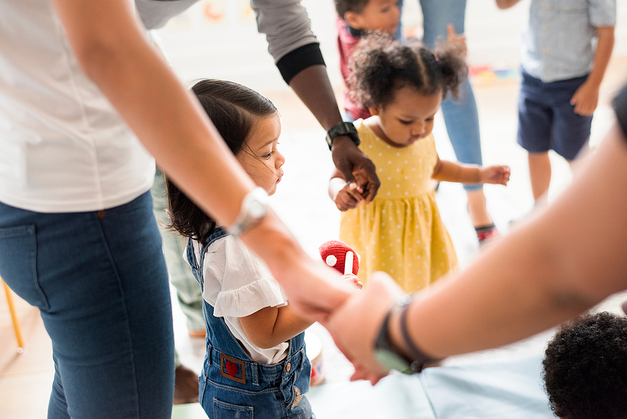 Preschool children and adults holding hands in a circle at little explorers class.